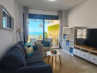 Una televisión o centro de entretenimiento en Alkan Suites con terraza en 1º linea de playa y piscina